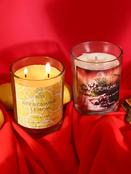 A bold and vibrant shot of lemon and spice scented candles against a rich red fabric. This composition is warm and inviting, perfect for highlighting festive or winter-themed fragrances.