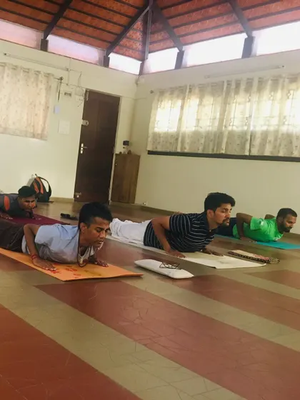 Students holding Bhujangasana, or cobra pose, during a Yogasanas session. This posture is excellent for strengthening the spine, but precision is key. I guide everyone to engage their muscles correctly to build strength safely and effectively.