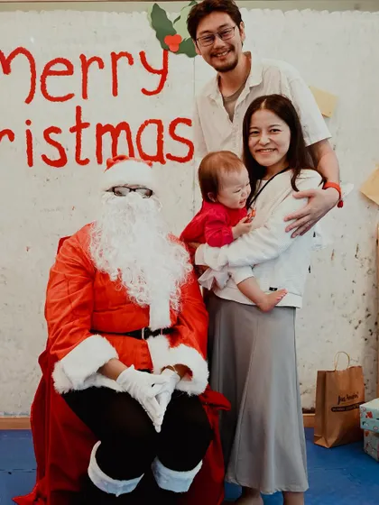 A family with a young baby gets their first photo with Santa.