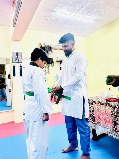 Awarding a green belt to a student who has successfully passed his exam.