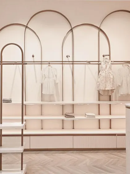 A detail of the wall-mounted display units, where overlapping rose gold arches create a beautiful and rhythmic pattern for hanging and shelving clothes.