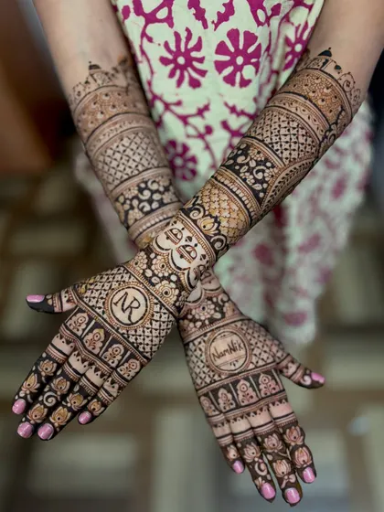 Namrata's wedding mehendi, personalized with the couple's initials "NR" and her name, woven into a rich tapestry of traditional patterns.