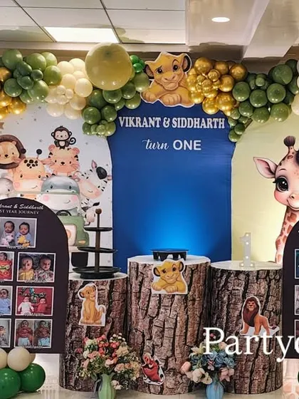 Another take on our popular jungle theme, this one for a first birthday. It features personalized photo boards, tree-trunk-style plinths, and a full balloon arch with green and gold accents.