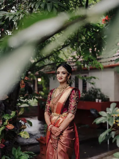 A beautiful bridal portrait framed by out of focus leaves in the foreground. This technique adds a sense of depth and intimacy, drawing the viewer's eye directly to the bride's graceful pose.