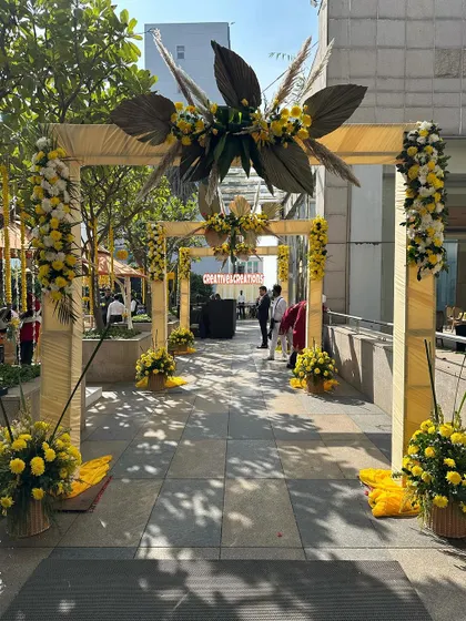 A modern and stylish entrance for a Haldi event. The wooden arches are decorated with yellow marigolds and dried pampas grass for a chic, bohemian look.