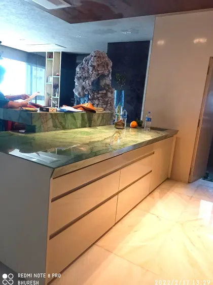 Another angle of the green marble island, showing the clean lines and handleless design of the base cabinets. This minimalist approach keeps the focus on the beautiful natural stone.
