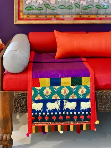 A one-of-a-kind reversible silk runner, custom-made with a patchwork of vibrant fabrics including a Pichwai-inspired cow print.
