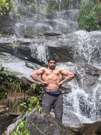 Showing off my back development or "wings" in front of a waterfall during a trek. Nature is the best gym.