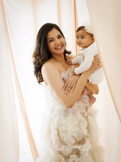 A mother's bright smile perfectly mirrors the joy of holding her child. This portrait is full of light, love, and happiness.