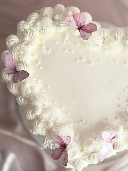 A top-down view of the white heart-shaped cake, showing the intricate piping around the edge.