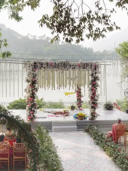 A serene lakeside mandap with delicate pink and white florals, offering a breathtaking natural backdrop for the ceremony.