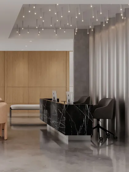 The reception desk is the clinic's focal point. The dramatic black marble with white veining is contrasted with warm wood paneling and soft upholstery on the waiting chairs, creating a balanced and harmonious ambiance.