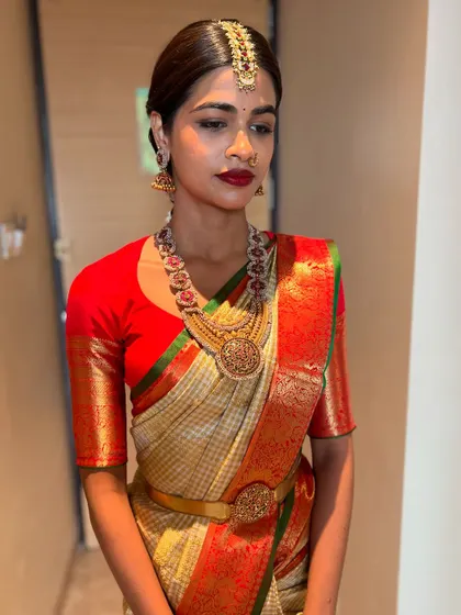 A portrait of a beautiful bride, her hair pulled back neatly to showcase her radiant face and traditional jewellery, leading into a classic braid.