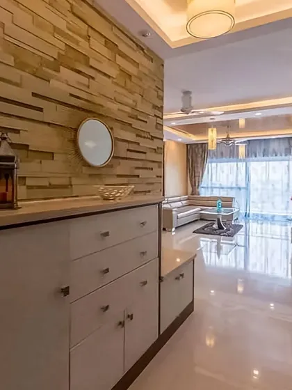This foyer design uses a stone-clad accent wall to create a textured, high-end feel. The simple cabinet provides storage while serving as a display surface, making the entrance feel both grand and grounded.