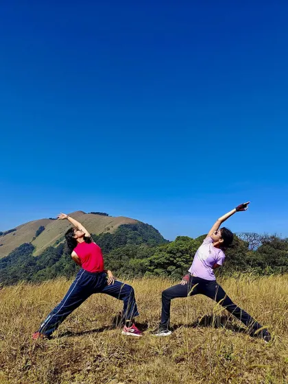 Two of us in Viparita Virabhadrasana, or reverse warrior pose, celebrating the end of a trek in the Coorg mountains. Partner yoga is a wonderful way to build trust and connection.