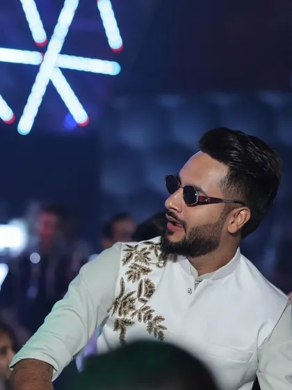 A candid shot of our client enjoying an event in his custom Indo-Western outfit. The detailed embroidery on the jacket adds a touch of elegance to his look.