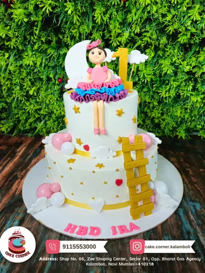 A whimsical two-tier doll cake with a "sitting on the moon" theme. The stars, clouds, and ladder details create a dreamy scene for Ira's first birthday.