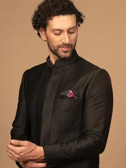 A detailed view of the black textured bandhgala, showing the quality of the fabric and the precision of the diagonal weave pattern. The patterned pocket square adds a pop of color and personality.