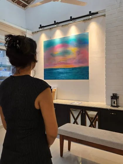 A visitor admires a colorful abstract landscape during Gurpreet Kaur's solo exhibition. Our gallery is designed to be a serene space for contemplation and appreciation of art.
