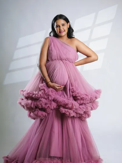 A happy and confident pose from the mom-to-be in our pink ruffled gown. This image captures the joyful spirit of pregnancy.
