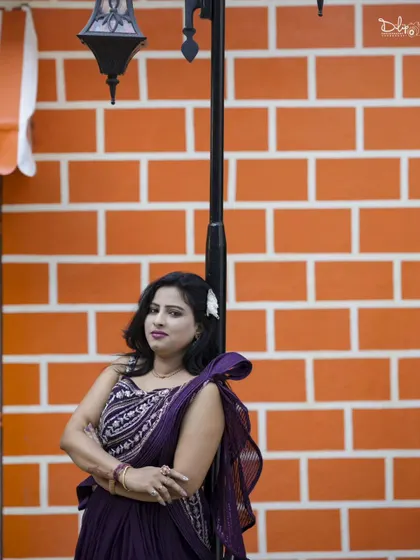 A stylish portrait by a lamppost against a bright orange brick wall.
