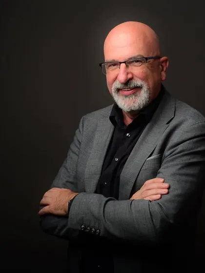 A classic crossed-arm pose for a senior leader. The lighting is sculpted to add depth and character, resulting in a powerful and sophisticated portrait.