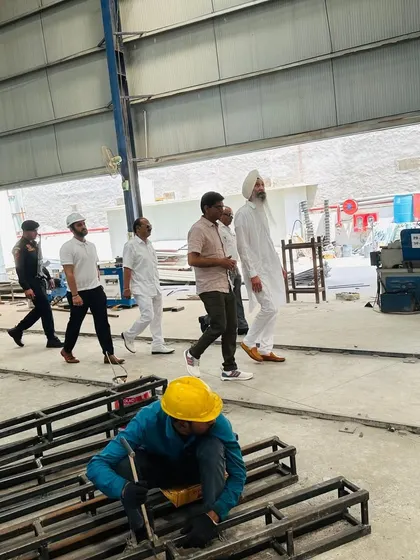 A worker fabricates steel frames on the factory floor while our team guides a client through the facility. This shows our hands-on approach and the skilled craftsmanship behind every product.