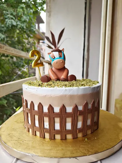 One of the cutest cakes I've ever made. This design features a little fondant pony sitting in a field, surrounded by a chocolate fence. It was for a second birthday party.