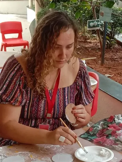 A participant carefully applying decoupage paper to her coaster.