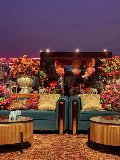 A lounge setup with modern teal sofas and round coffee tables, filled with vibrant floral arrangements. This area shows how contemporary comfort can be integrated into a grand, traditional theme.
