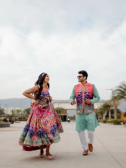 A fun and colorful shot of a couple during their Mehendi, with the bride in a vibrant pink and blue lehenga.