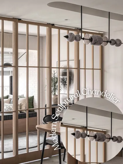 A modern sculptural chandelier made of stone-like elements hangs in this dining area. It acts as a stunning centerpiece, blurring the line between lighting and art, and is visible through the wooden grid partition.