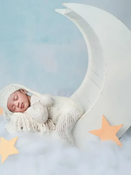 Our little boy sleeping peacefully in his own dreamland. The crescent moon prop and soft clouds create a magical and serene atmosphere for a newborn portrait.
