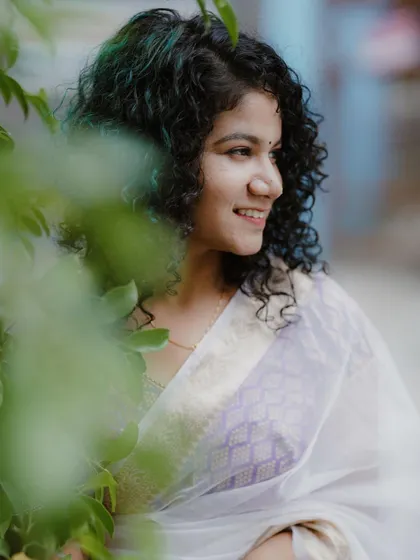 A close-up shot peeking through the leaves. This creative framing adds an element of intimacy and playfulness to the traditional Onam portrait.