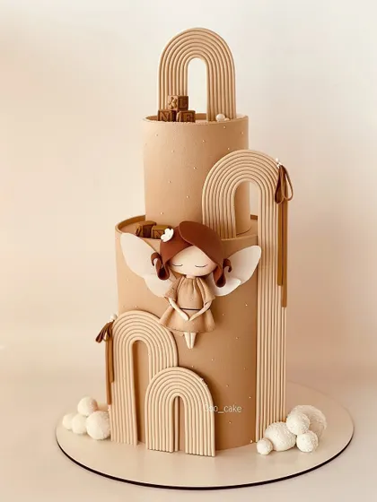 A two-tiered, pastel brown angel-themed cake with a modern, boho feel.