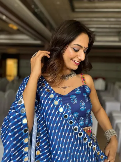 A happy, smiling client ready for Navratri. Her soft glam makeup with a hint of shimmer is the perfect complement to her traditional mirror-work attire.
