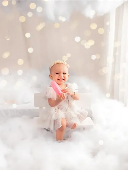 A little fairy coming your way, sitting on a bench in the clouds. The bokeh lights in the background add an extra layer of sparkle to this enchanting setup.