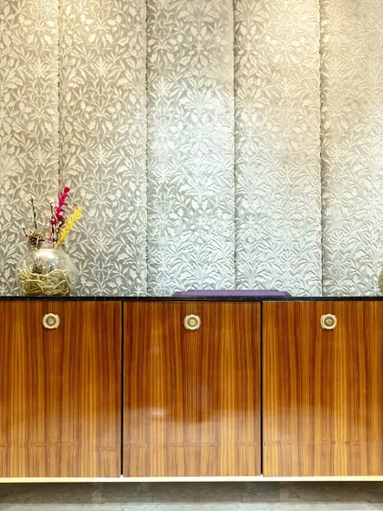 A frontal view of the bespoke storage console, highlighting the rich grain of the wood veneer against the soft, patterned fabric panels on the wall behind it.