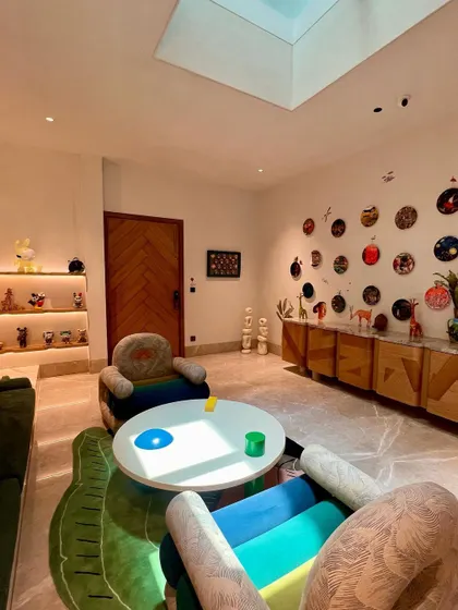 We designed this playful and inspiring room around custom armchairs and a central coffee table. The space is filled with personality, from the colorful furniture and unique wall decor to the curated collection of art toys on illuminated shelves.