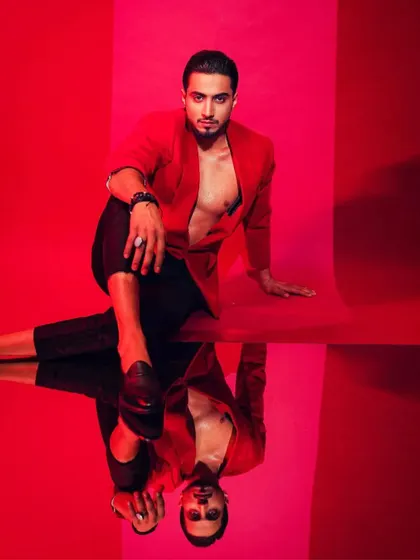 A bold, high-contrast look for Mr. Faisu. The open red blazer against a stark red background creates a visually arresting image, showcasing a confident and daring side of his style.