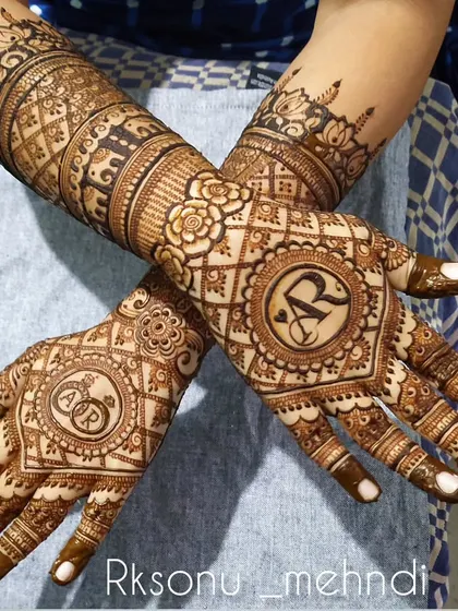 A bespoke ring ceremony design featuring the couple's initials "AR" inside a beautiful circular frame. The hands are covered in a mix of geometric and floral patterns, extending up the arms.