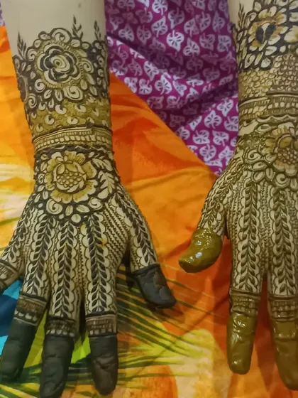 A traditional design featuring leaf-like patterns (bel) on the fingers and a dense, detailed palm design.
