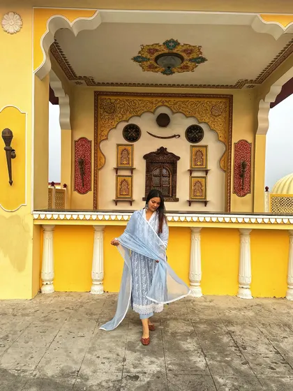 A beautiful light blue printed suit set, perfect for a daytime event. The color is soft and serene, and the backdrop of Nahargarh Fort in Jaipur adds to the royal vibe.