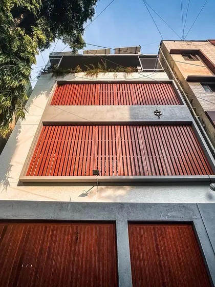 A low-angle view of the Basavanagudi residence, highlighting the texture of the wooden louvers and the clean lines of the minimalist facade.