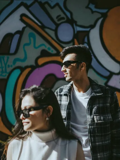 A cool, edgy portrait of the couple against a vibrant graffiti wall in LA. Their sunglasses and relaxed poses reflect the city's laid-back, artistic vibe, showcasing a different side of their pre-wedding story.