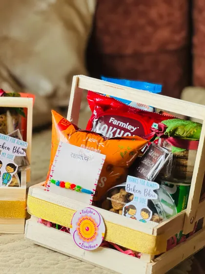 A close-up of a wooden crate Rakhi hamper, showing the mix of traditional and modern snacks.