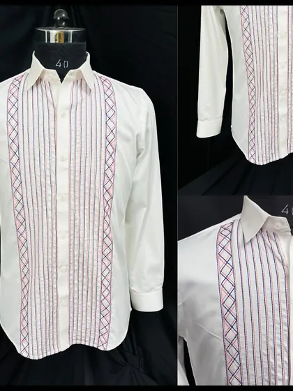 A detailed look at the white shirt with a pleated front and vertical embroidered lines. The design is inspired by classic tuxedo shirts but updated with a touch of color.
