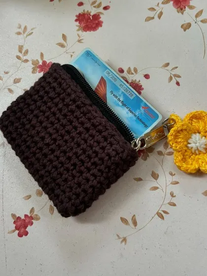 A small crochet wallet, perfect for holding a few cards and some cash. The flower charm adds a sweet touch.