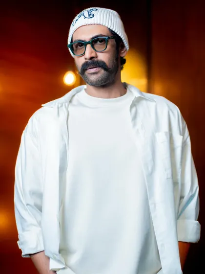 A portrait of Rana. The beanie and glasses add a touch of personality to the clean, minimalist look.