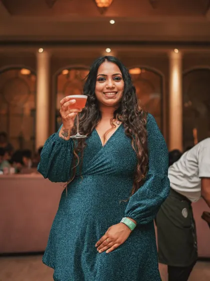 A guest dressed for a celebration, cocktail in hand. The elegant interior provides a beautiful backdrop, making everyone feel like they are part of something special.
